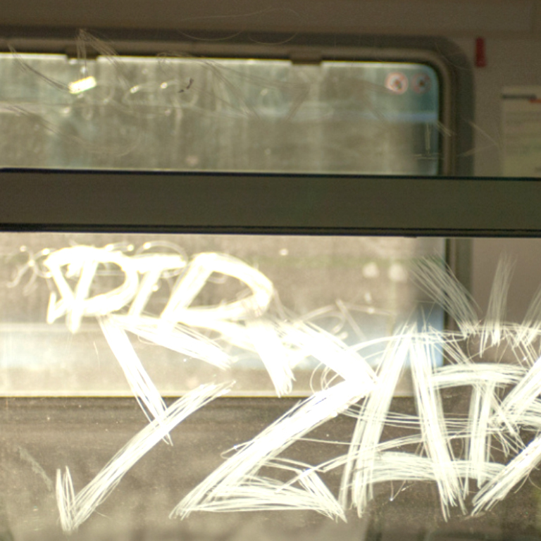 Graffti on a train window, showcasing anti-graffiti window film