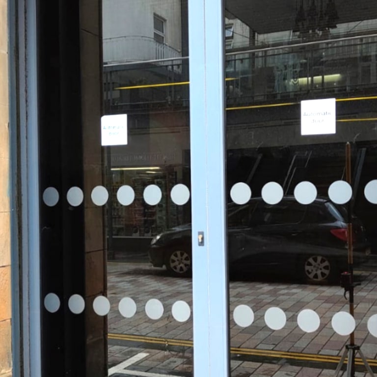 Two front doors showing privacy film and patterned manifestation dots.